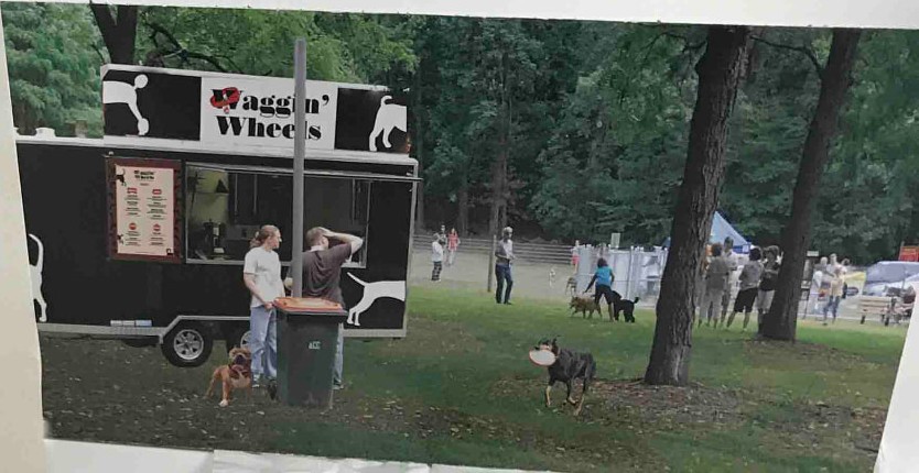 Composited scene of the black Waggin' Wheels food truck at a dog park