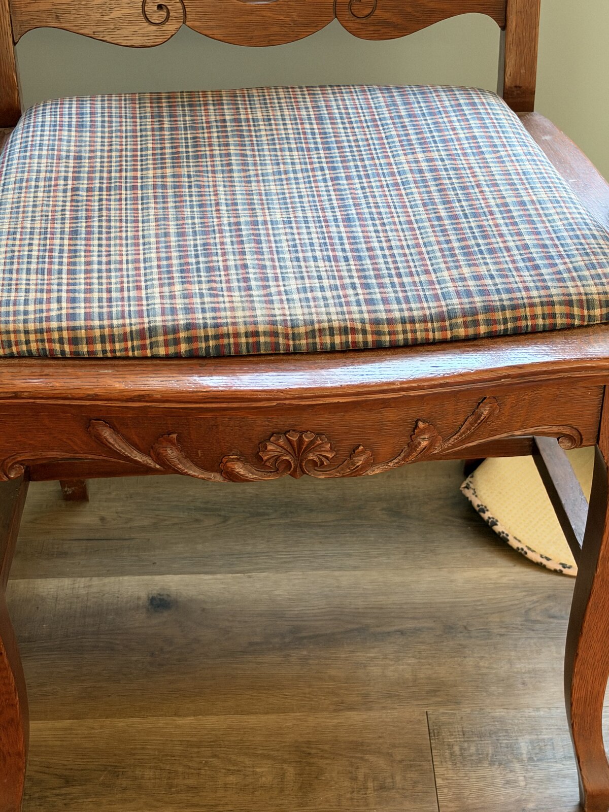 Front of the armchair: plaid upholstered seat above a carved apron and curved legs