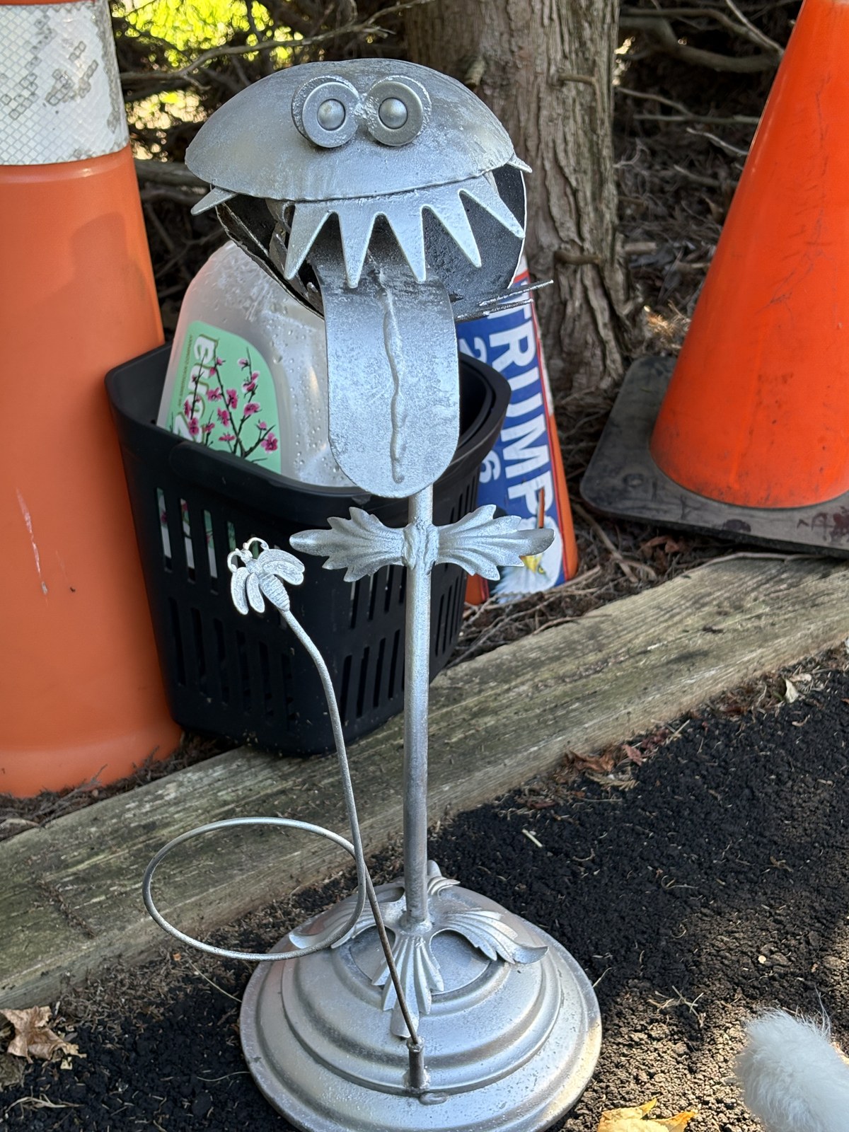 Before: weathered bare-metal garden sculpture of a toothy, plant-like creature