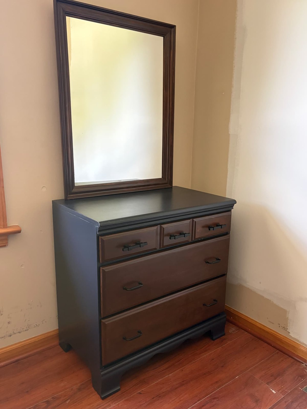 The restored dresser with its framed mirror: black painted case and base, dark-stained drawer fronts and matte black hardware