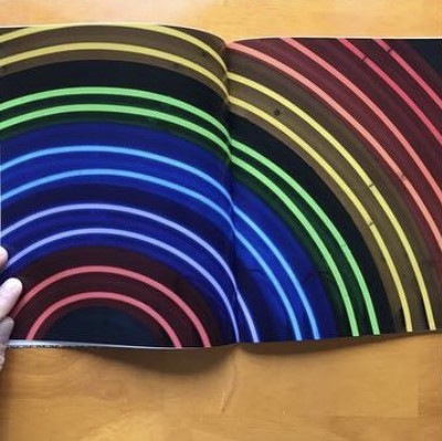 Full-bleed spread of curved rainbow neon tubes